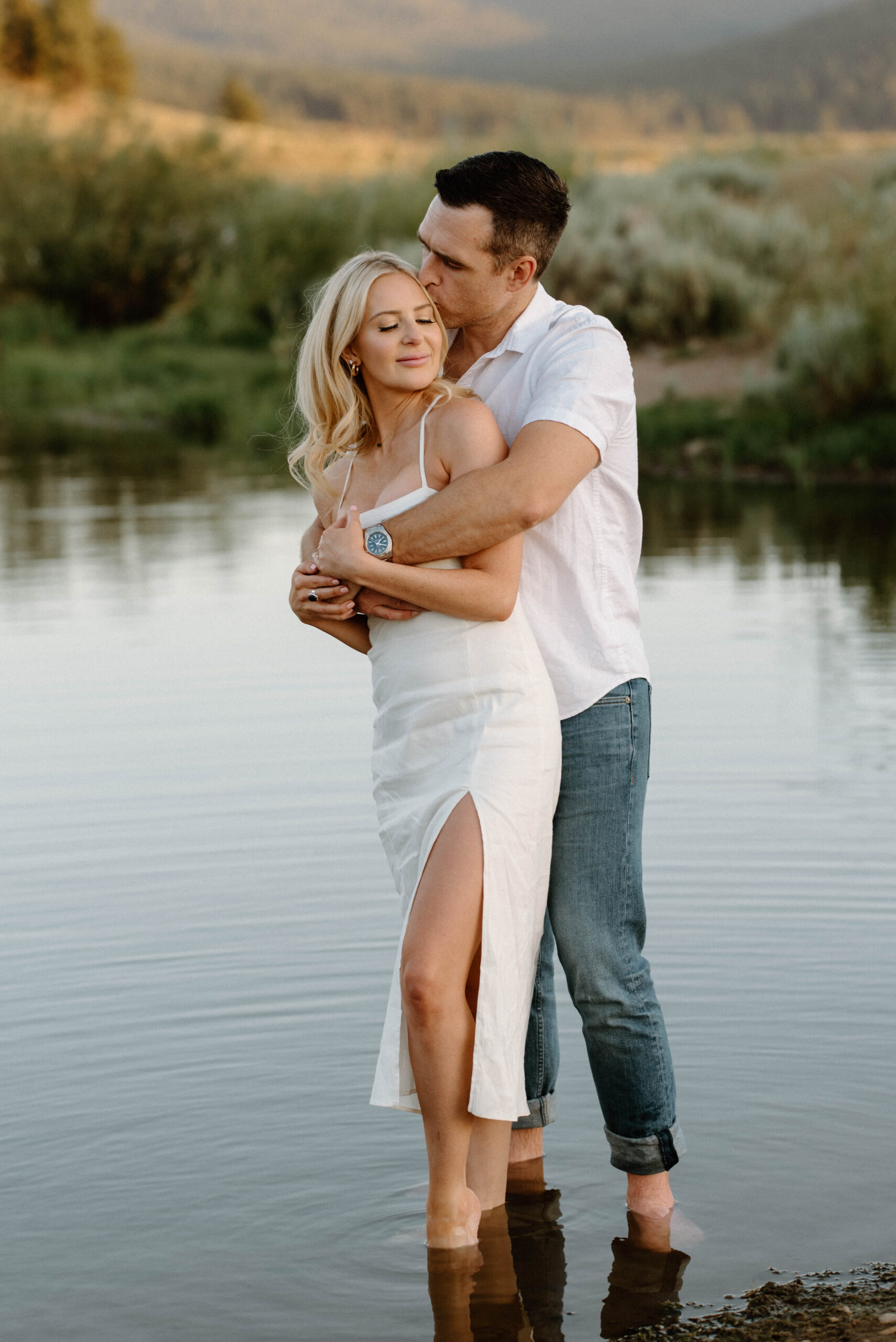 couple embracing standing in a lake as the sun goes down